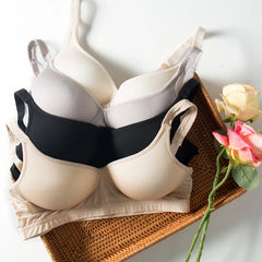 Silk bra set featuring seamless wireless design in beige and black, placed in a woven basket with pink roses.